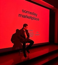 a man sitting on a chair in front of a red screen