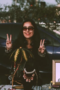 a woman holding a peace sign in front of a car