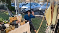 a woman sits at a table in front of a table full of pots