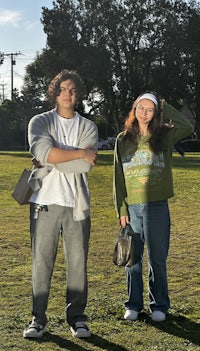 a young man and woman standing in a park